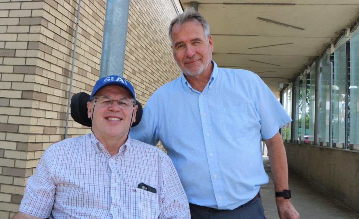 Two men smile at the camera